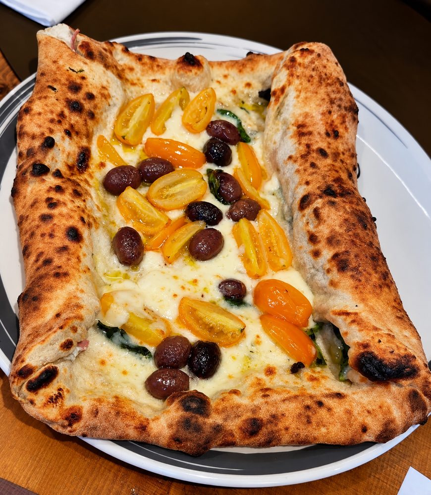 Pizza con cornicione ripieno di salsiccia, mozzarella e friarielli, pomodorini gialli e olive taggiasche